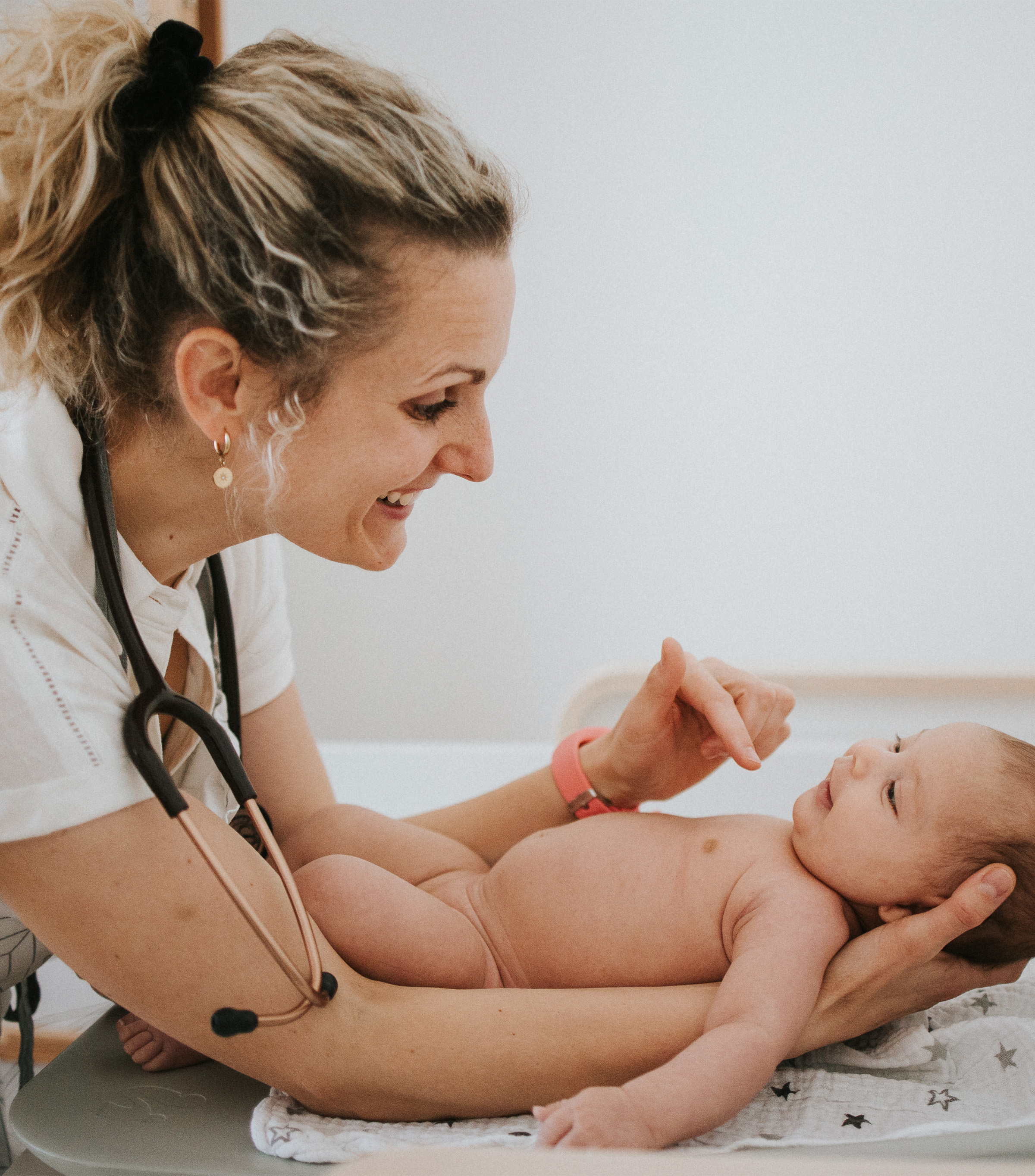 Hebamme lächelt ein Baby auf dem Wickeltisch an